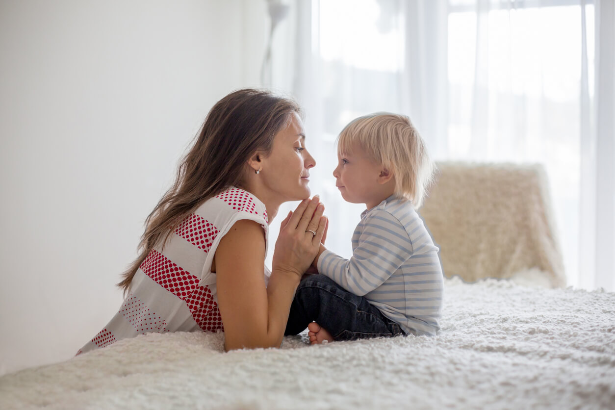 A mother kneeling down to calmly look into her toddler's son's eyes.