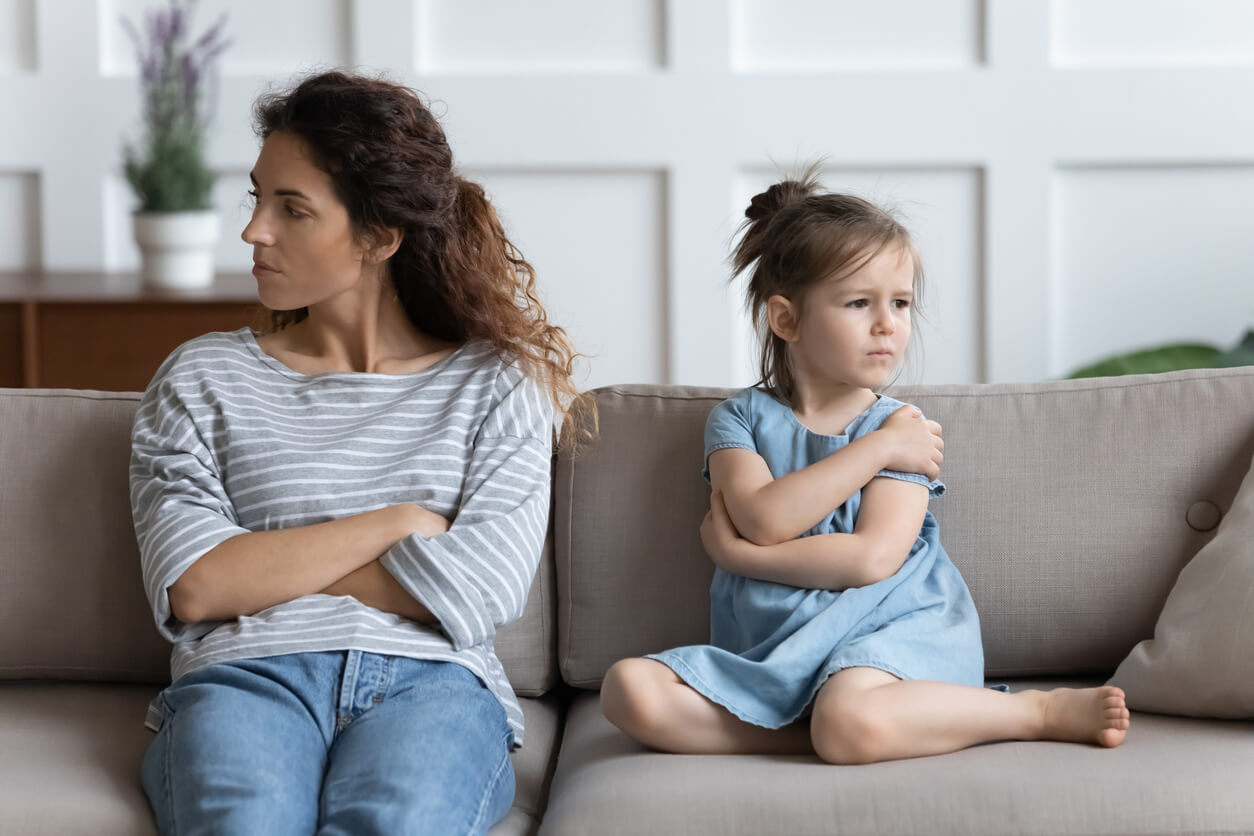 Une mère et sa fille qui se tournent le dos sur un canapé.