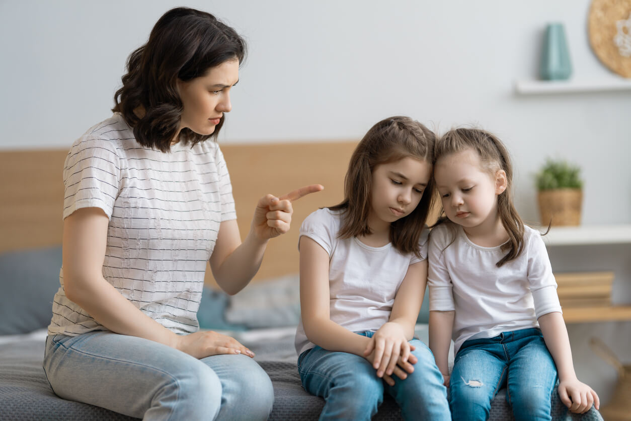 A mother pointing angrily at her daughters.