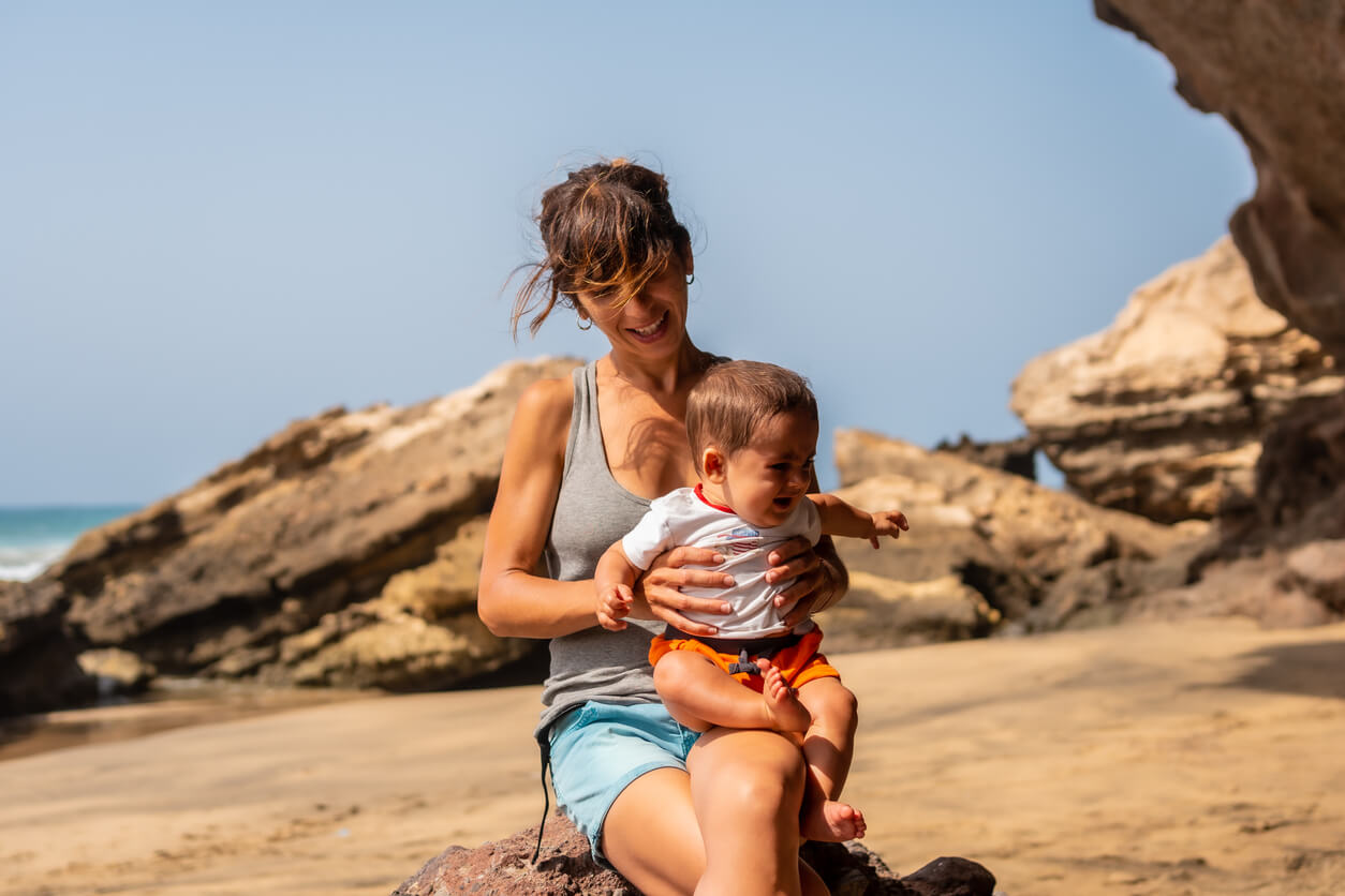 A woman at the beach with her baby.