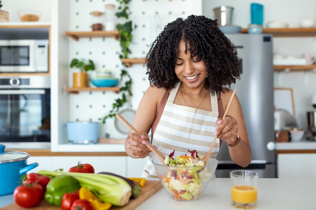 A black woman preparing a fresh tossed salad.