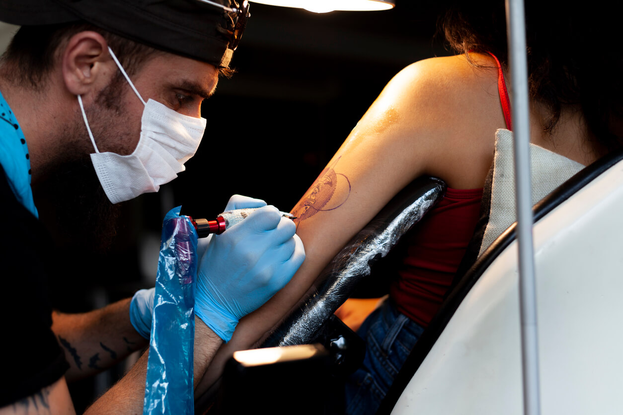 A woman getting a tattoo on her arm.