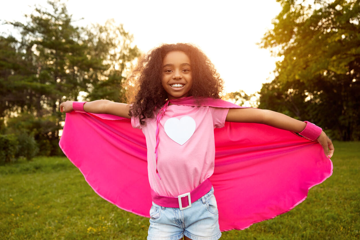 A black girl wearing a pick cape.