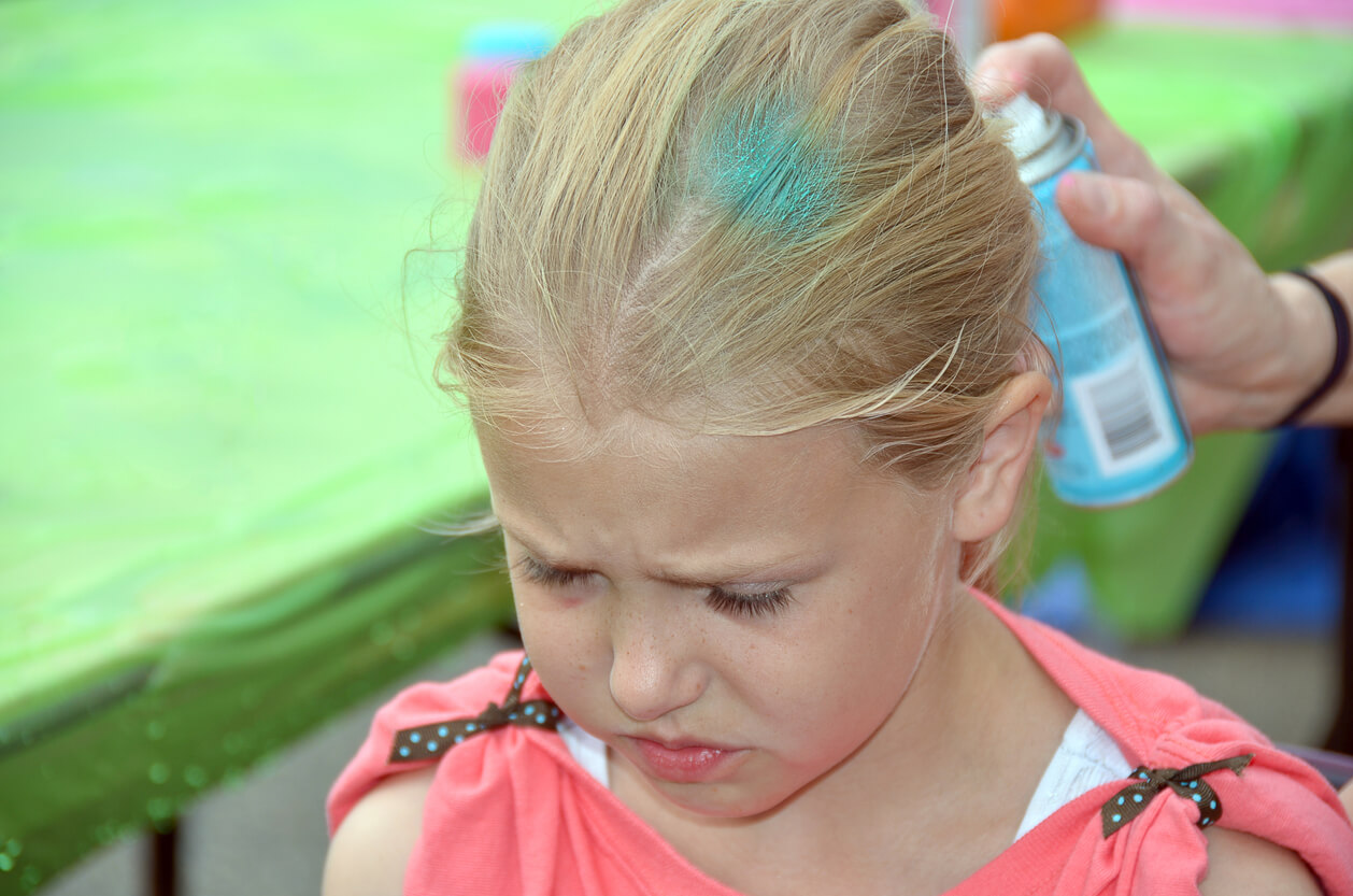 A person coloring a child's hair with temporary spray.