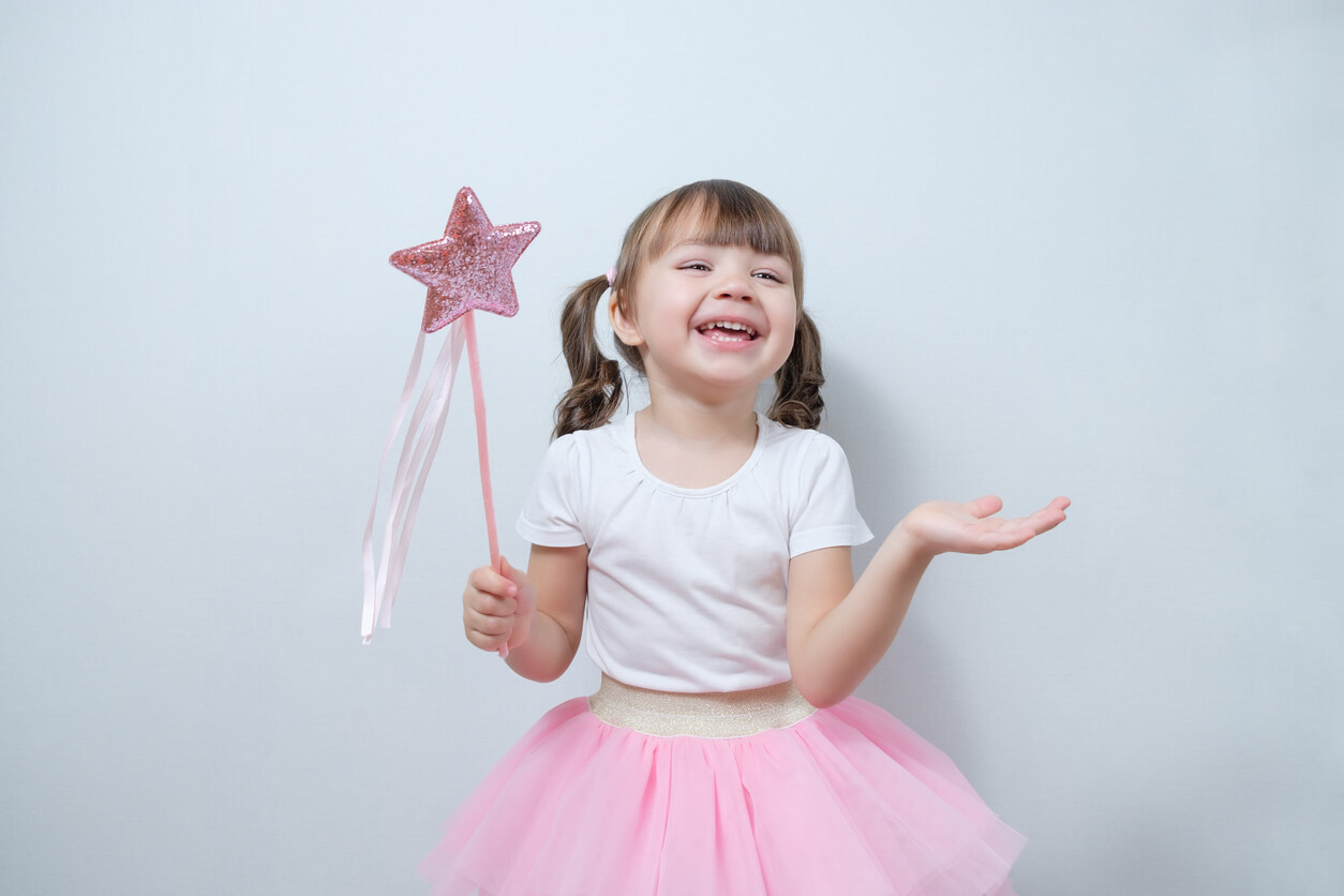 A little girl wearing a tutu and holding a pink wand.