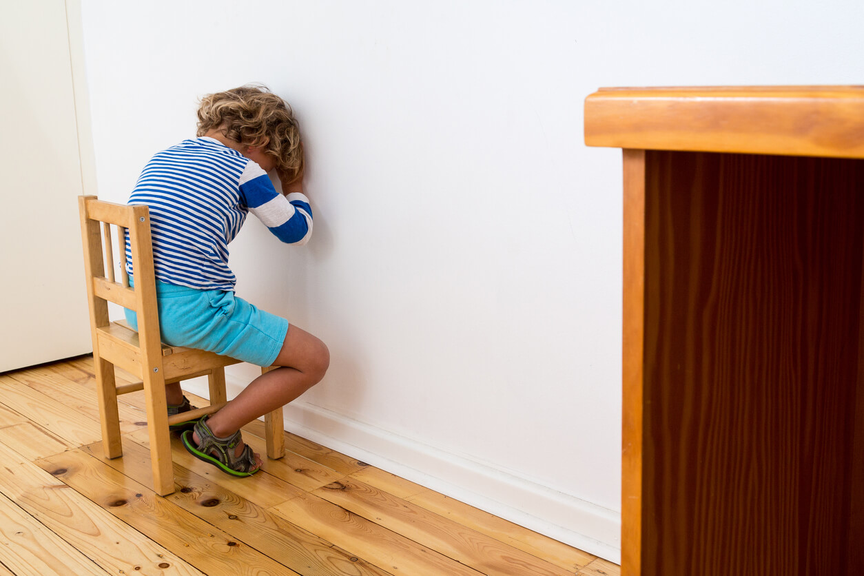 A child sitting in a chair facing a wall.