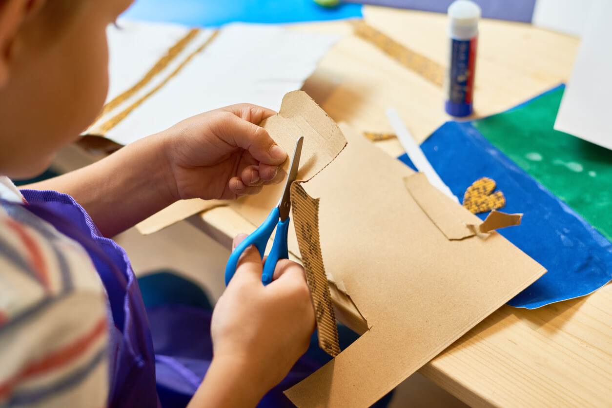 A small child cutting carboard to make a craft.