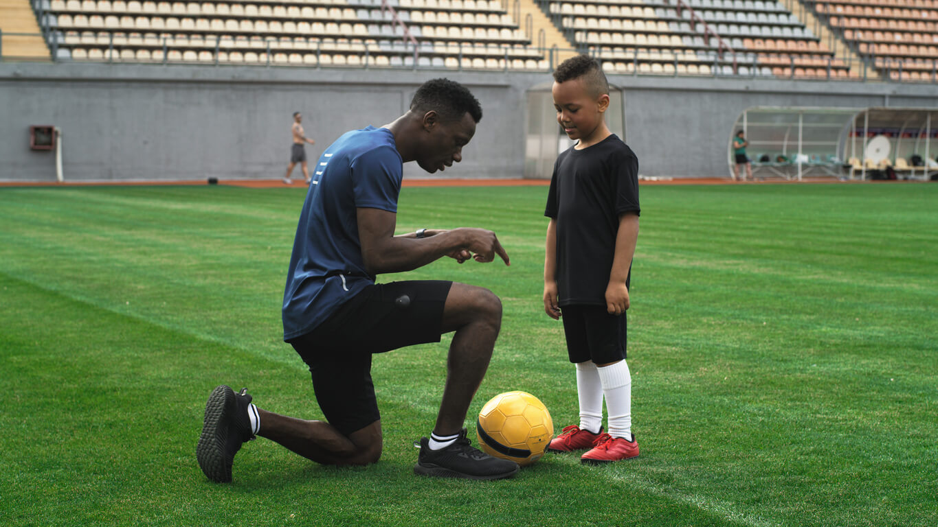 Un enfant et un adulte qui apprennent à jouer au football.