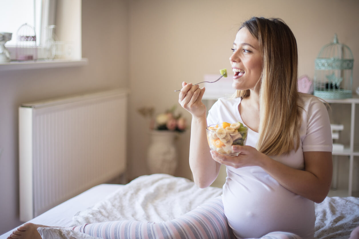 A pregnant woman eating fruit salad.