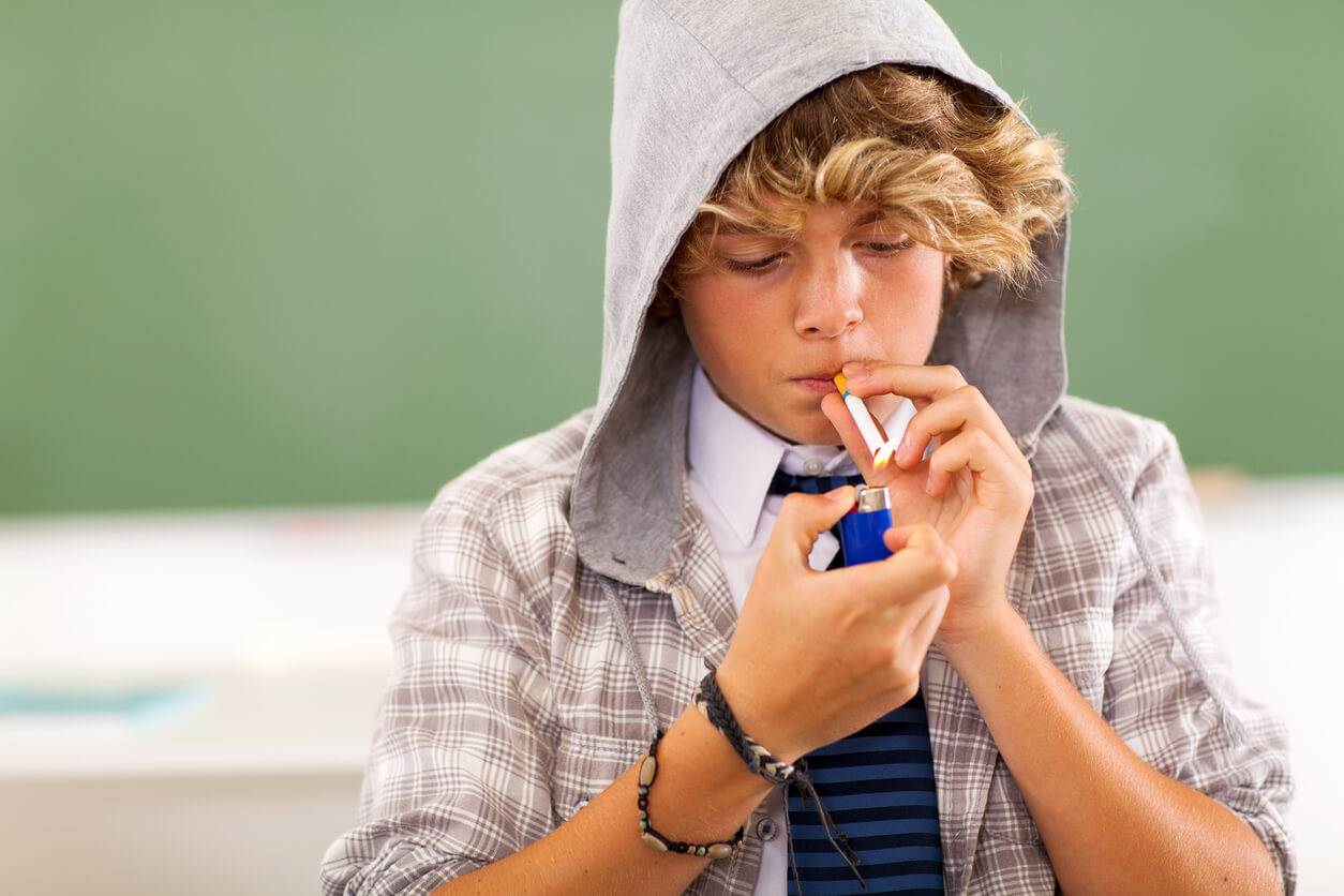 A teenager lighting a cigarette.
