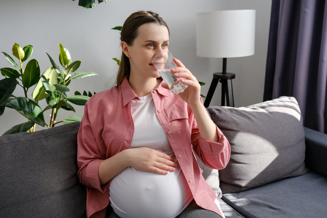 A pregnant woman drinking a glass of water.