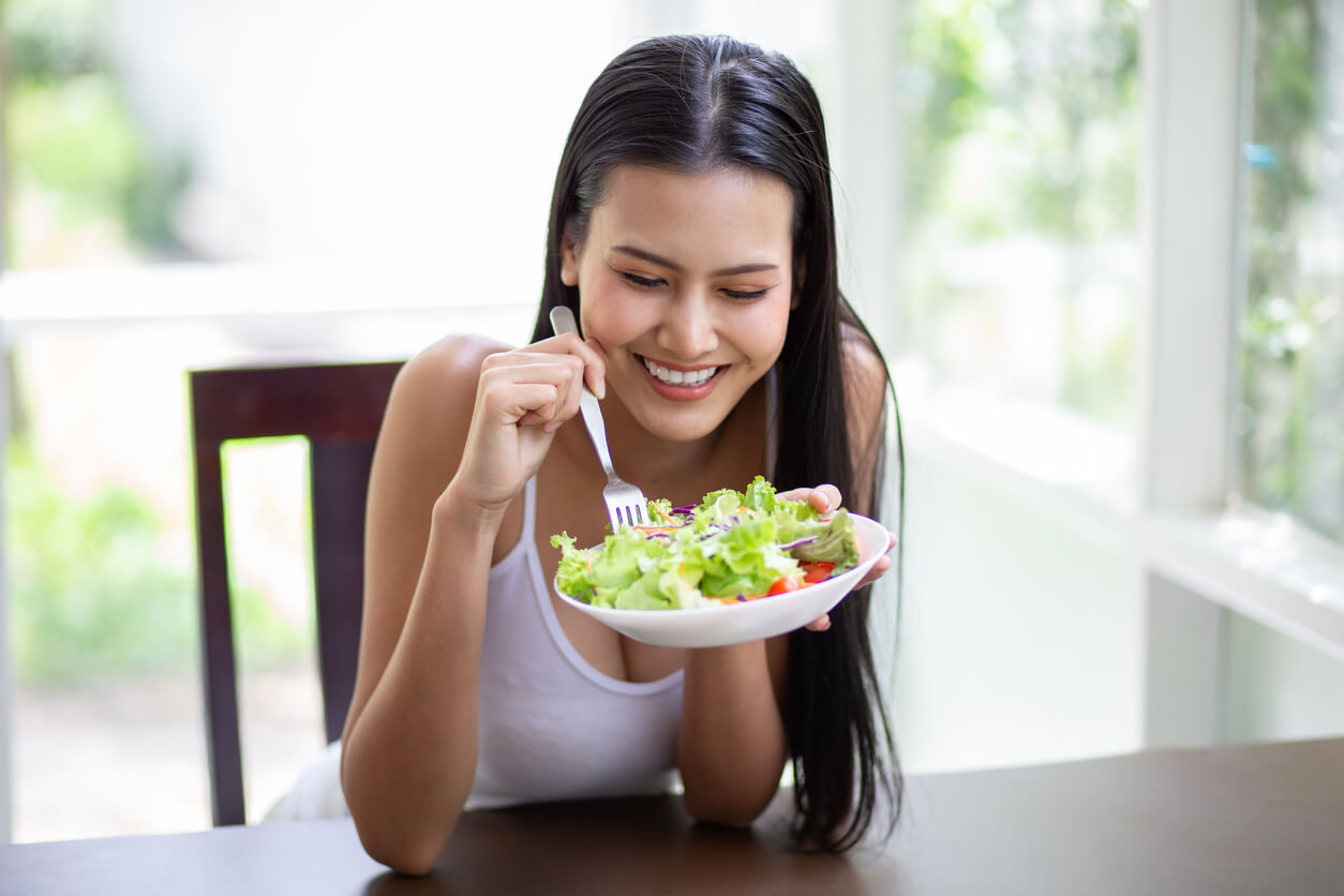 Une jeune femme qui mange une salade.