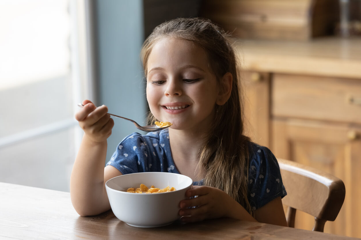 A young girl eating a bowl of cereal with plant-based milk.