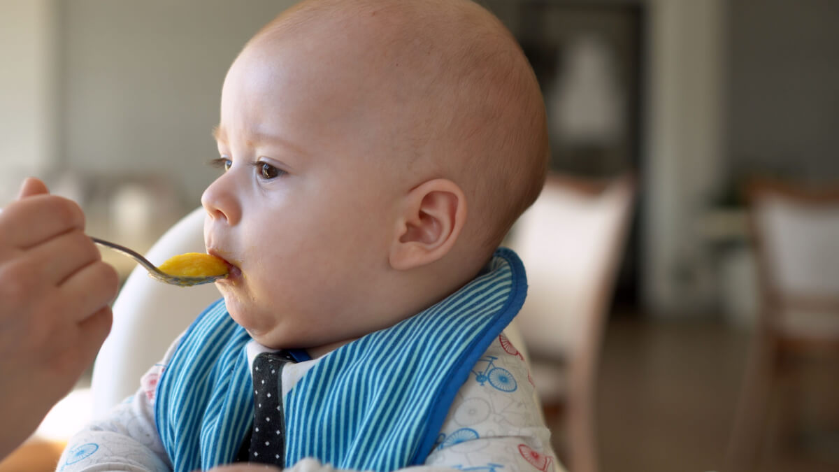 Bebé comiendo papilla que le podría causar carotenemia.